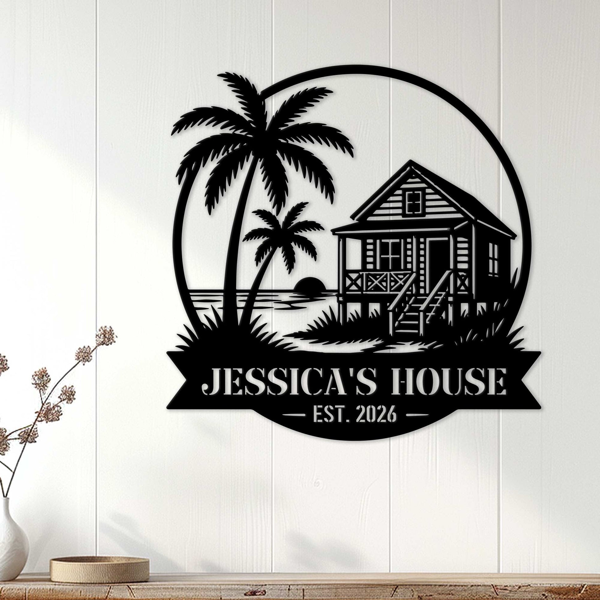 Black beach house wall sign displayed on white paneling as coastal home decor