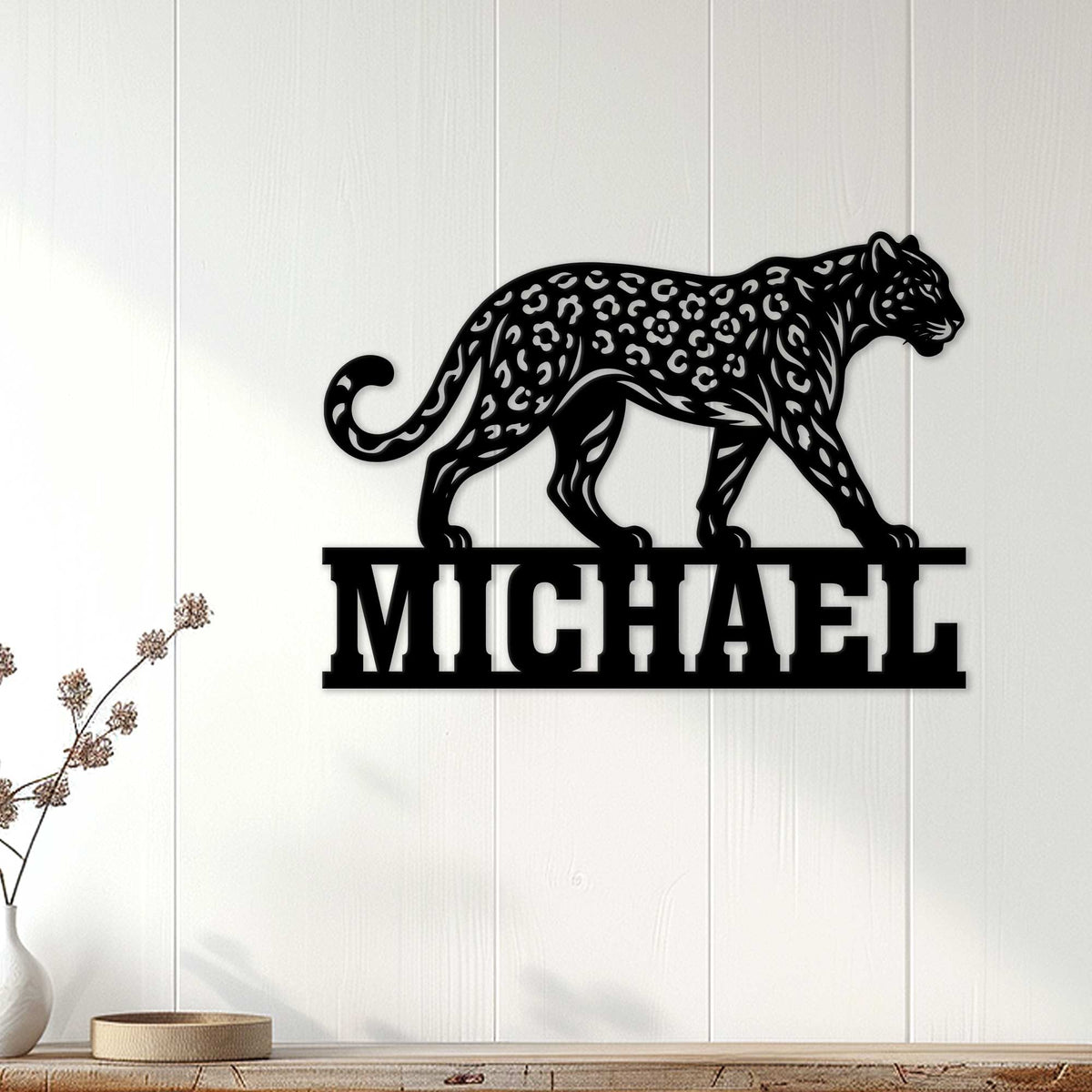 Black leopard wall sign displayed on a light paneled wall above a modern console