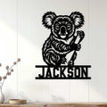 Black koala wall sign displayed on a light wood-paneled wall in a home interior