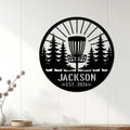Disc golf wall sign displayed on a white paneled wall, featuring a basket framed by evergreen trees