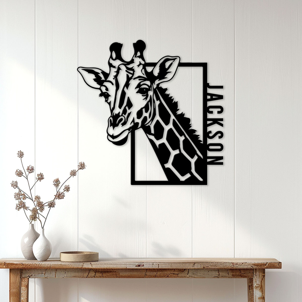 Giraffe metal wall sign displayed on a bright white paneled wall above a console table