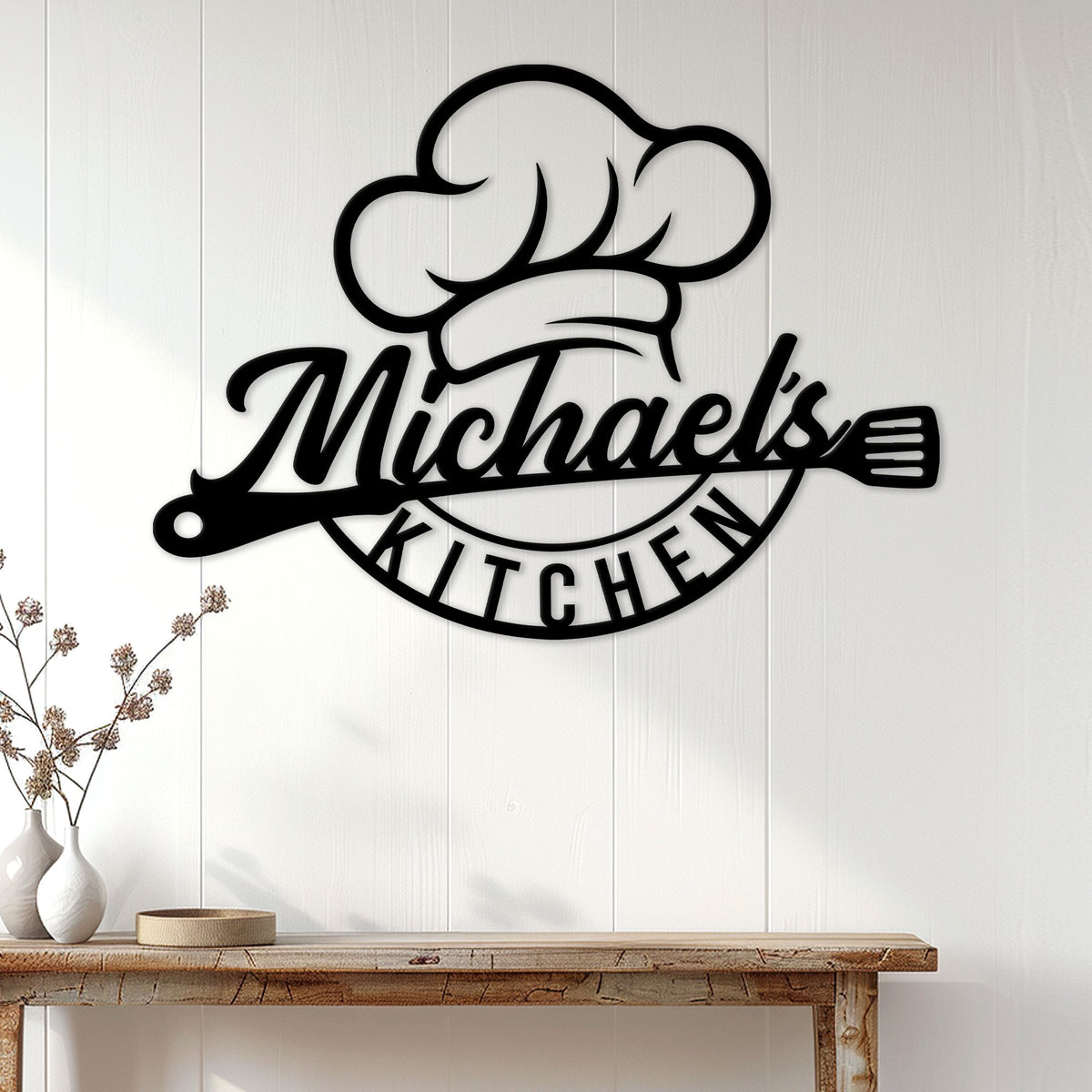 Black chef kitchen metal sign styled on a light paneled wall above a wood console table