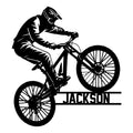 Mountain biking metal sign featuring a helmeted rider performing a dynamic wheelie on a mountain bike