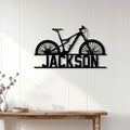 Black mountain bike metal sign displayed on a white paneled wall above a rustic console table