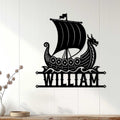 Black Viking dragon ship wall sign displayed on a light wood-paneled wall in a home interior