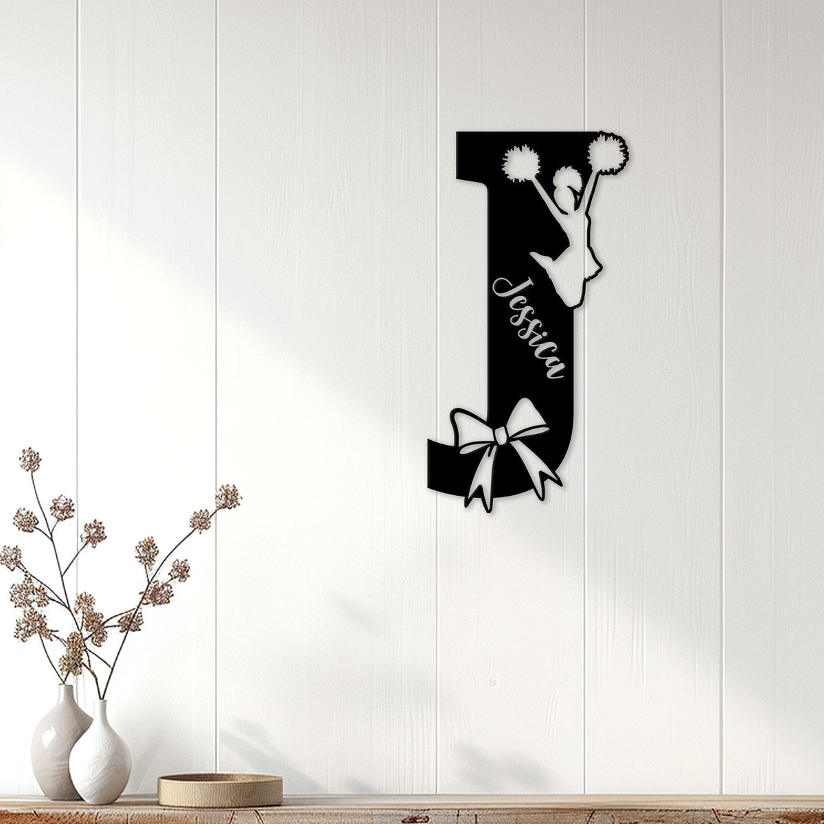 Cheerleader metal wall sign displayed on white paneled decor with a jumping silhouette and decorative bow