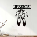 Black ballet shoe wall sign displayed on a light wood-paneled wall as bedroom decor