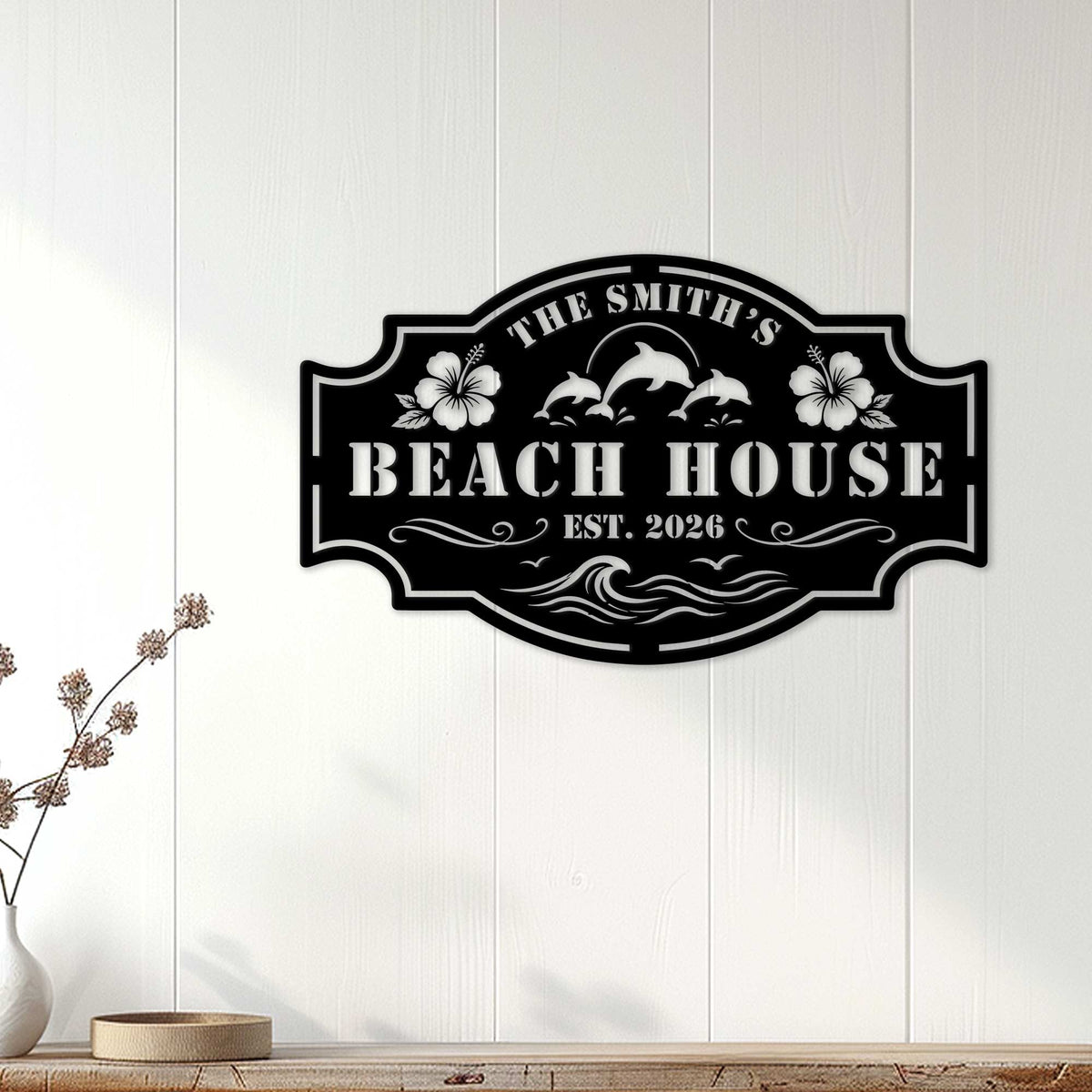 Black beach house wall sign displayed on white wood paneling in a coastal home setting