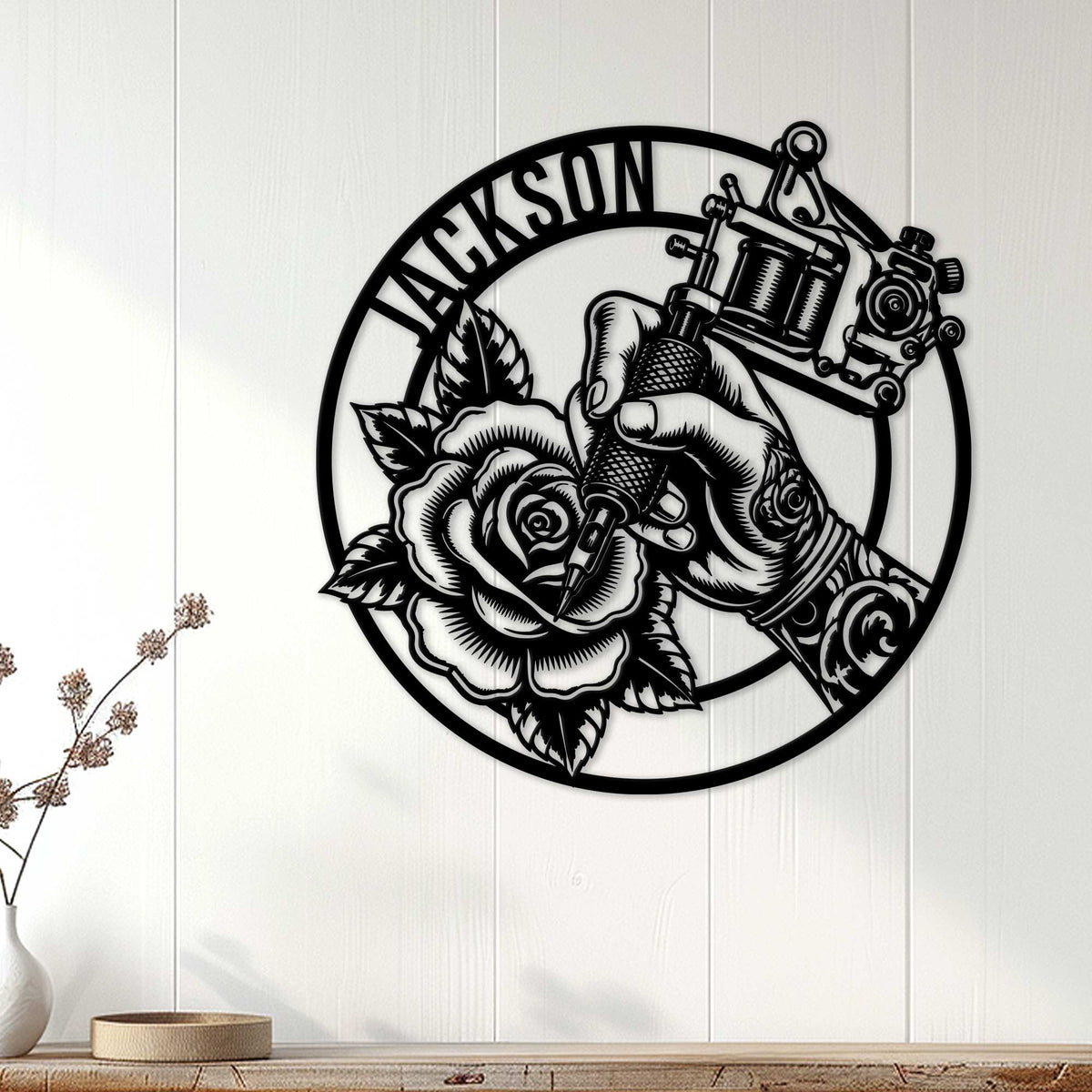 Tattoo studio wall decor displayed on white paneling, featuring a hand, tattoo machine, and detailed rose