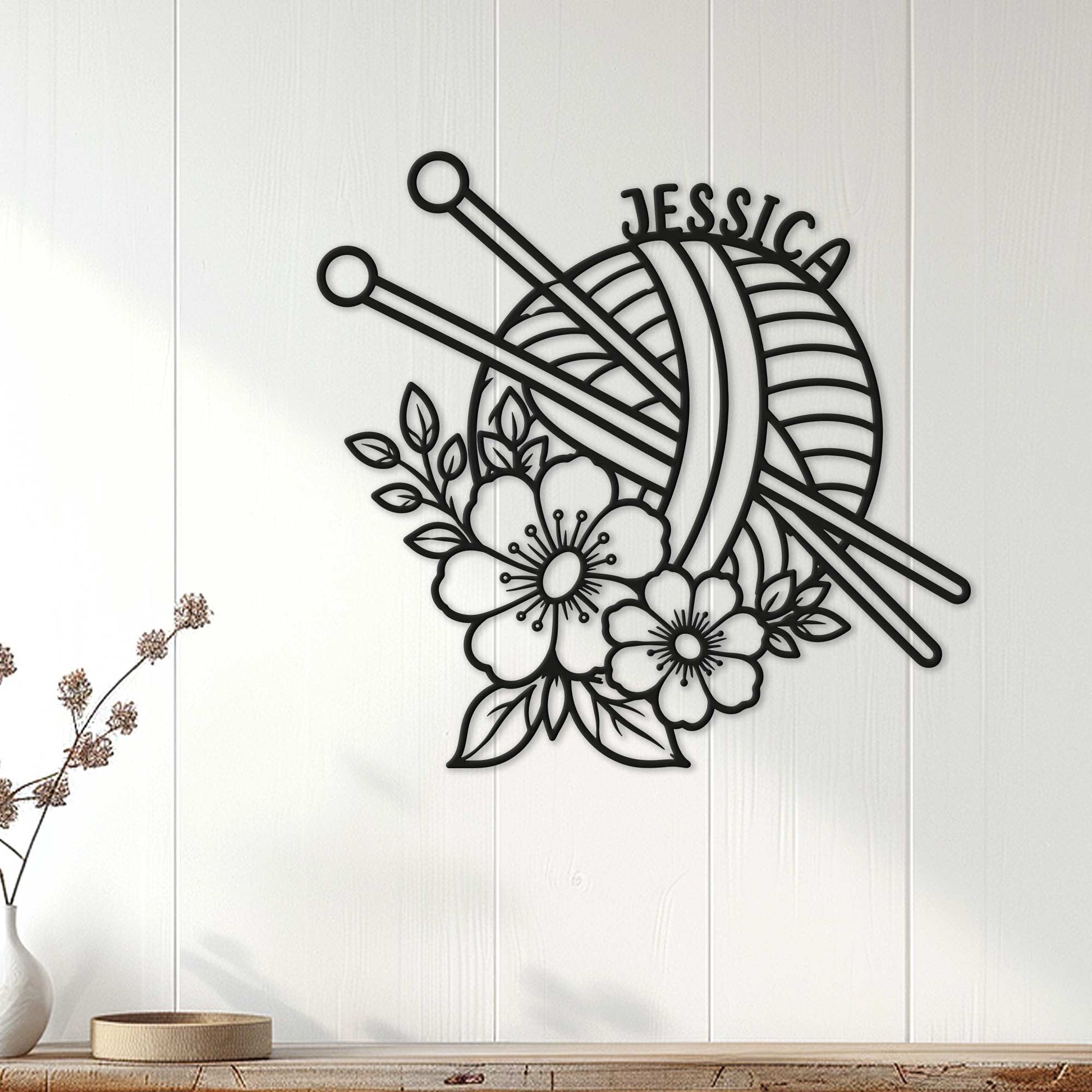 Black knitting wall sign with yarn and needles displayed on a light wood-paneled wall