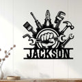 Mechanic wall sign displayed on white paneling, featuring a gear, tools, wrench, hammer, and bold industrial artwork