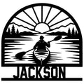 Kayak metal sign featuring a paddler on a calm lake beneath mountains, pine trees, and a rising sun