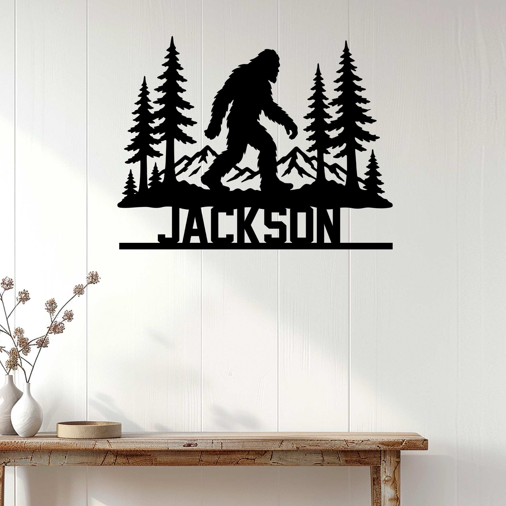 Bigfoot silhouette wall sign displayed on a light wood-paneled wall above a console table