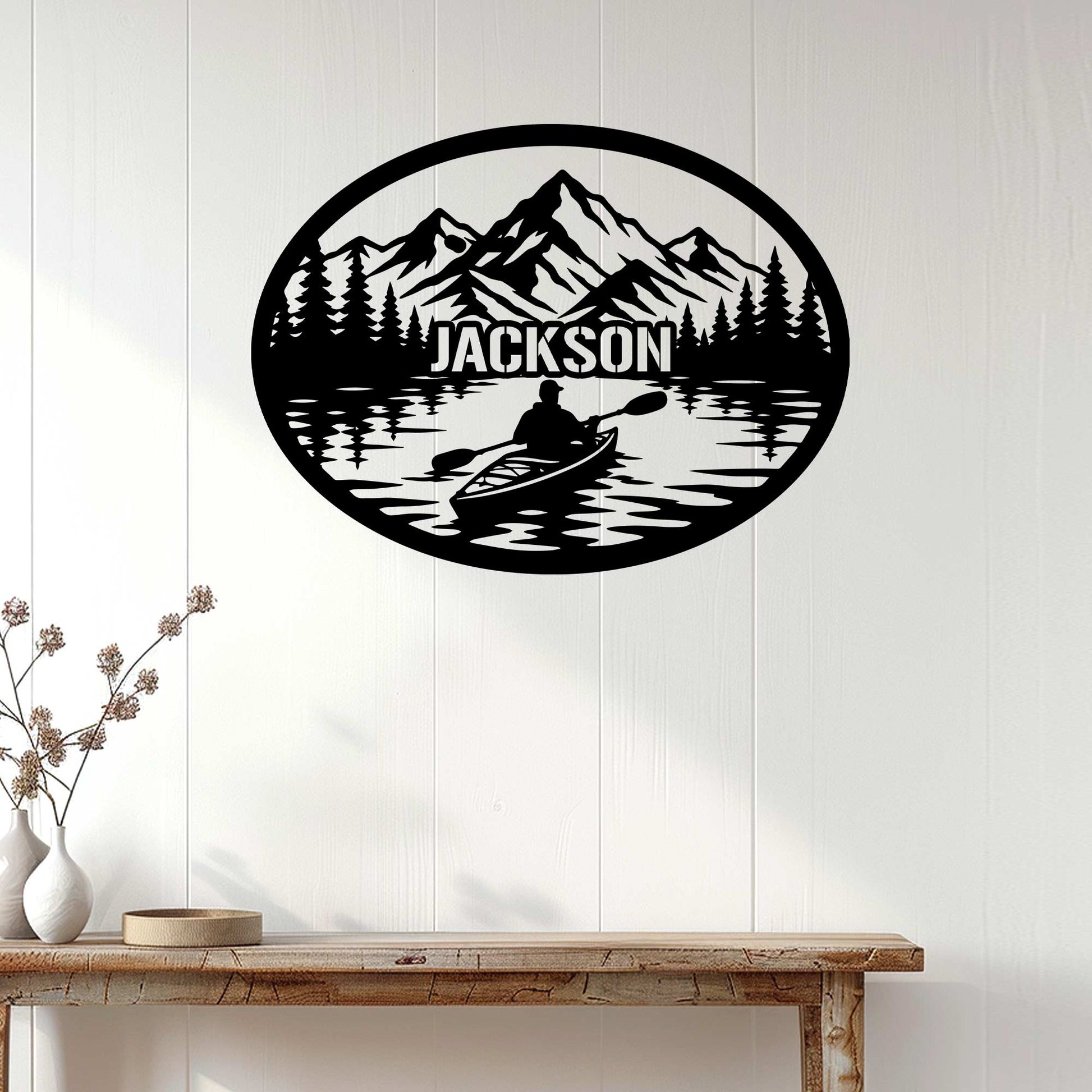 Mountain lake kayak metal sign displayed on a light wood-paneled wall above a console table