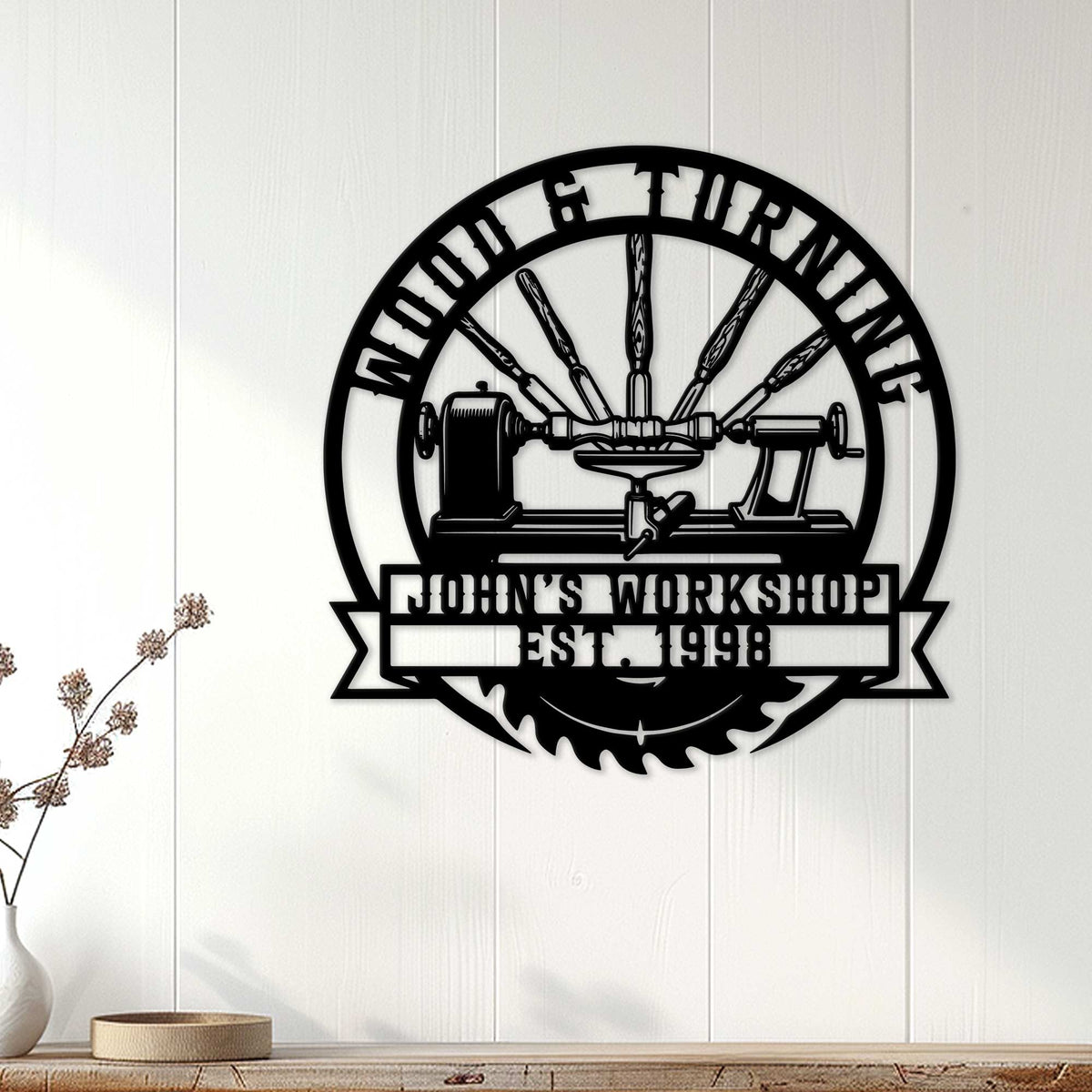Black woodturning workshop metal sign displayed on a white paneled wall in a home decor setting