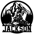Snowmobile metal sign featuring a rider crossing a mountain landscape with pine trees in bold black silhouette