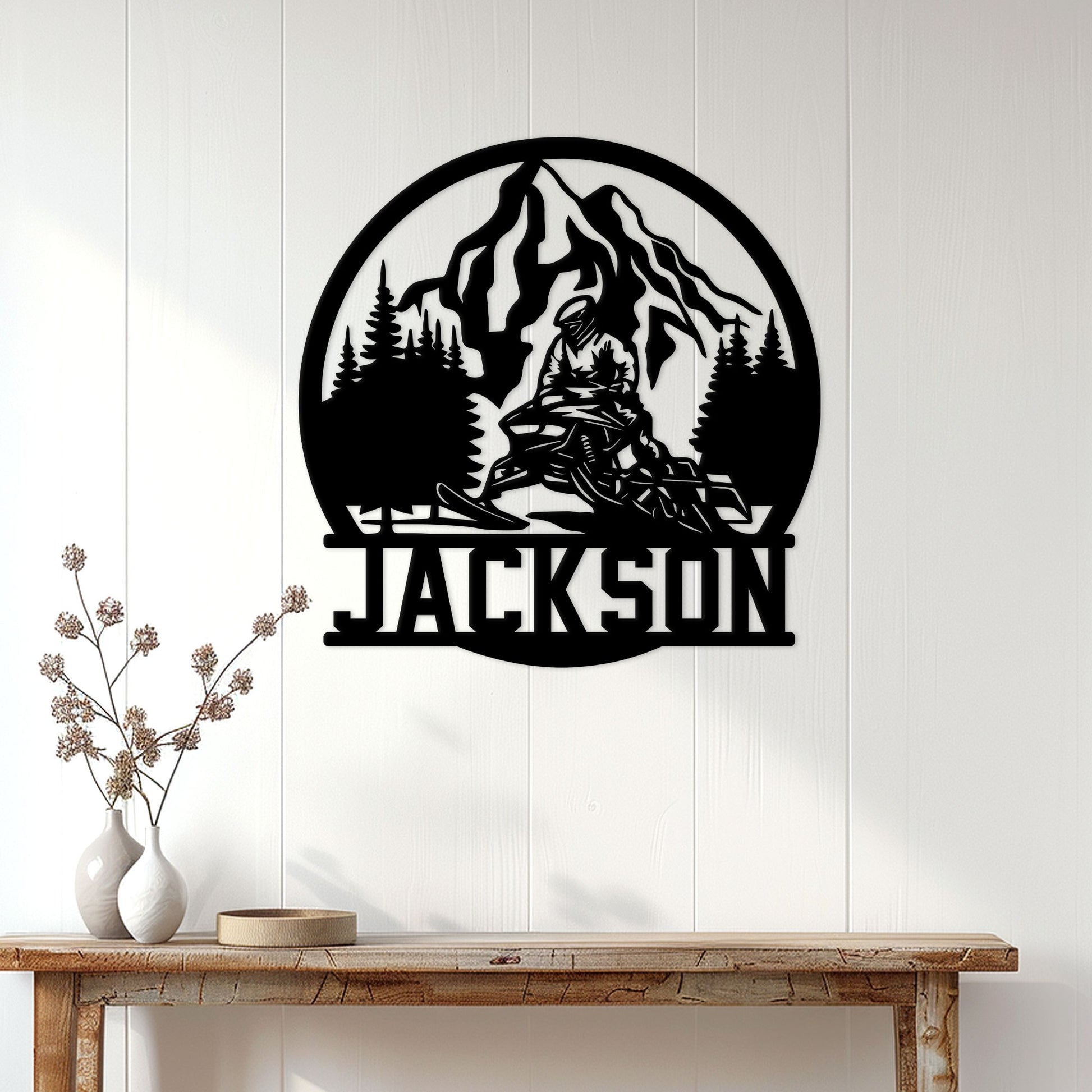 Snowmobile wall decor displayed above a wood console, featuring a mountain, pine forest, and rider silhouette