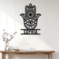 Black Hamsa hand evil eye wall sign displayed above a console table in a bright home entryway