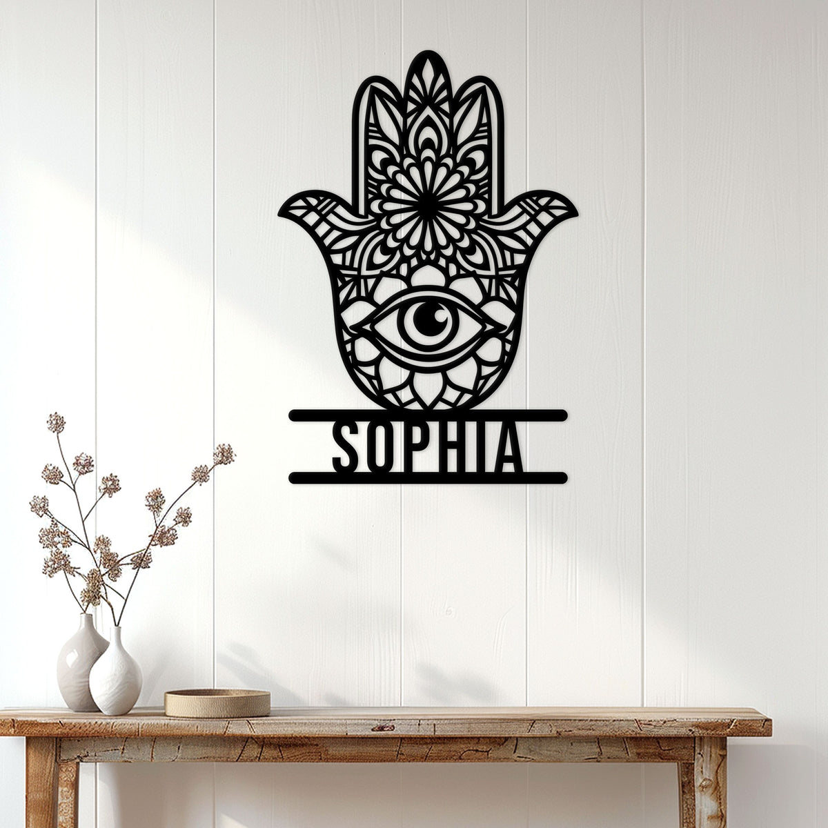 Black Hamsa hand evil eye wall sign displayed above a console table in a bright home entryway
