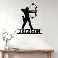 Custom archer metal wall sign displayed on a white paneled wall above a rustic console table