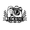 Black photographer metal sign featuring hands holding a camera, leafy accents, and an ornamental banner