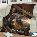 Deer throw blanket draped across a sofa, showing a buck surrounded by trees, mountains and autumn foliage
