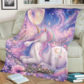 Unicorn throw blanket draped across a sofa, featuring a pastel rainbow mane, flowers, moon, and stars