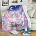 Unicorn throw blanket displayed on a sofa with pastel clouds, stars, rainbow mane, and cosmic night sky