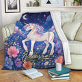 Magical unicorn throw blanket draped over a sofa with colorful flowers, stars, and a deep blue night sky