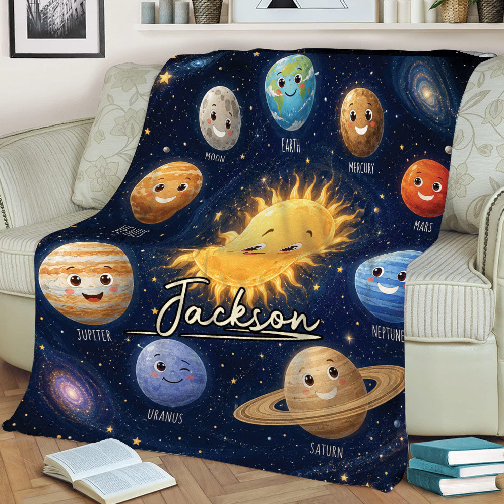 Space-themed throw blanket draped over a sofa with smiling planets and galaxy details