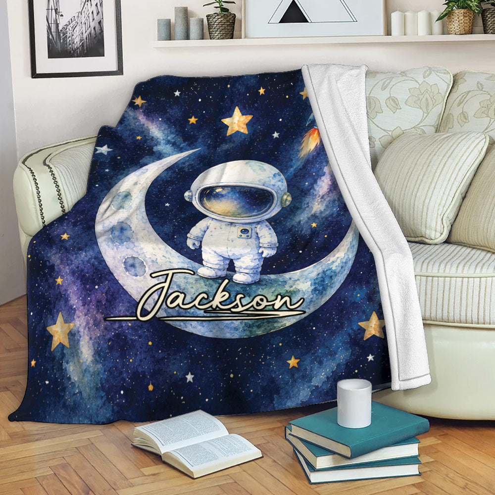 Astronaut throw blanket displayed on a sofa with moon, rocket, stars, and galaxy artwork