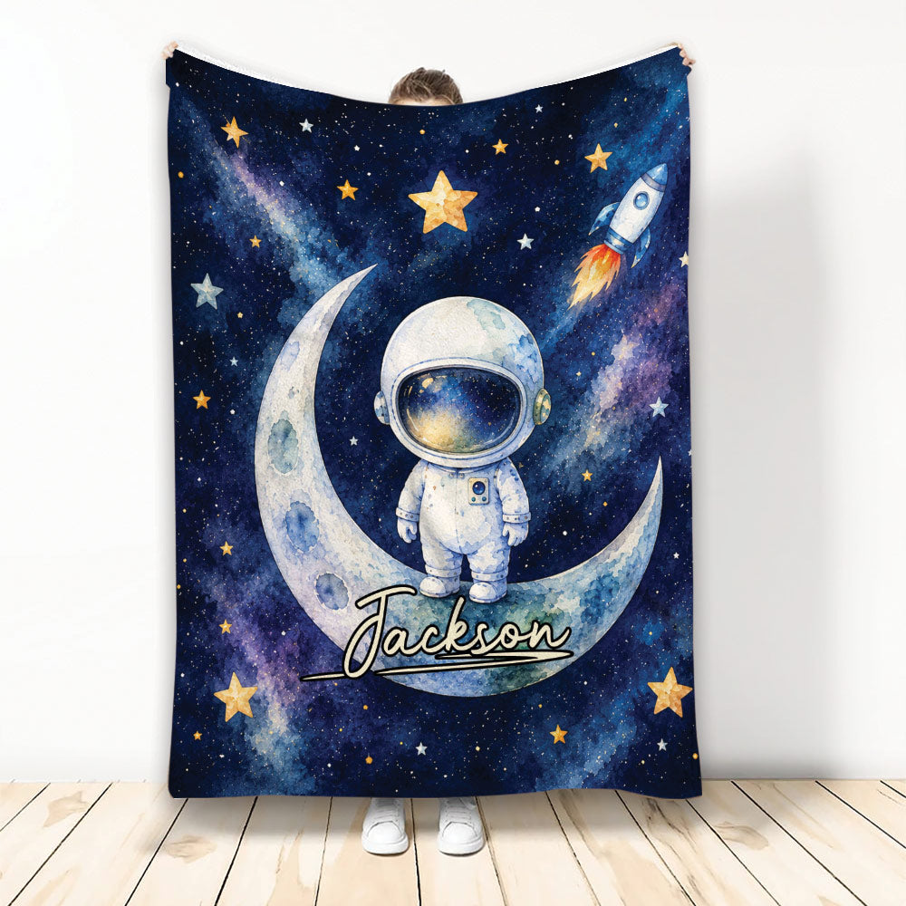 Astronaut blanket featuring a watercolor moon, rocket, stars, and deep blue galaxy artwork