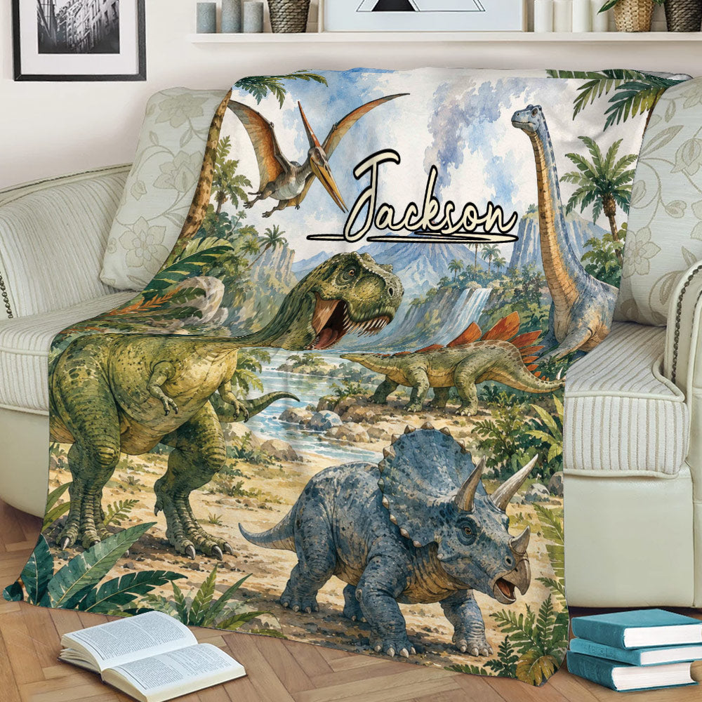 Dinosaur throw blanket displayed on a couch with T-rex, triceratops, stegosaurus, and waterfall artwork