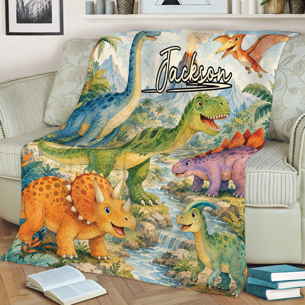 Close view of a colorful dinosaur throw blanket featuring a T-rex, long-neck dinosaur, triceratops and jungle scenery