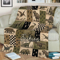 Dinosaur blanket styled across a sofa with illustrated T-rex, triceratops, stegosaurus, and pterosaur artwork