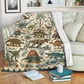 Dinosaur blanket draped over a sofa with vintage prehistoric artwork, tropical foliage, and a cozy reading setting
