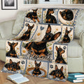 Close lifestyle view of a Miniature Pinscher throw blanket on a couch with daisy panels and multiple dog portraits