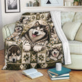 Alaskan Malamute blanket draped over a sofa, featuring dog portraits, white daisies, and earthy decorative patterns