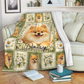 Pomeranian throw blanket draped over a sofa with fluffy dog portraits, white daisies, and green patchwork details