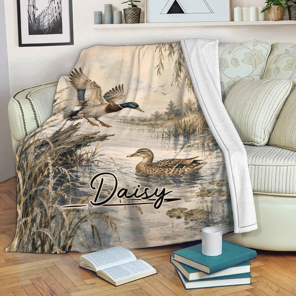 Duck hunting throw blanket displayed on a couch with mallards, reeds, and wetland artwork