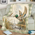 Mallard duck hunting blanket draped over a couch with cattails, marshland, and vintage outdoor artwork