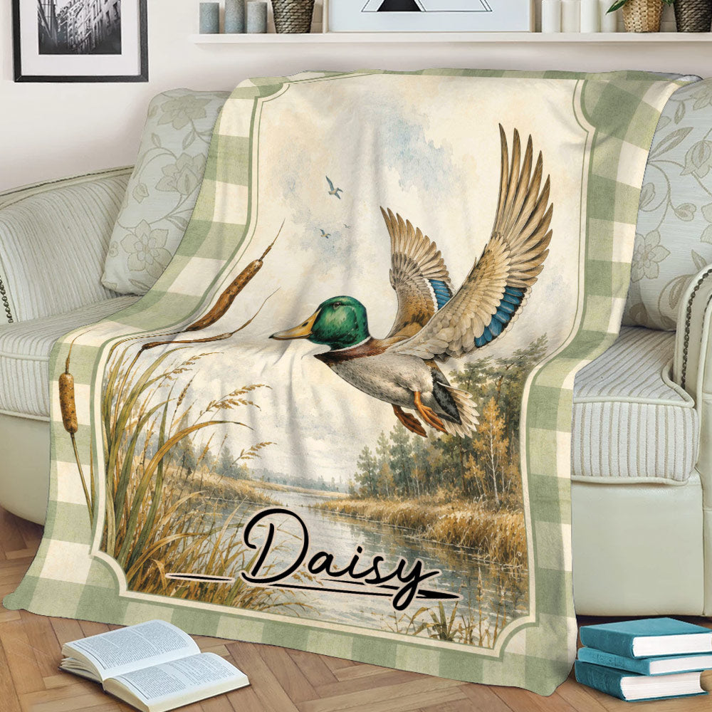 Mallard duck hunting blanket draped over a couch with cattails, marshland, and vintage outdoor artwork