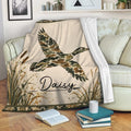 Duck hunting throw blanket displayed on a sofa with flying duck artwork, cattails, and camouflage details