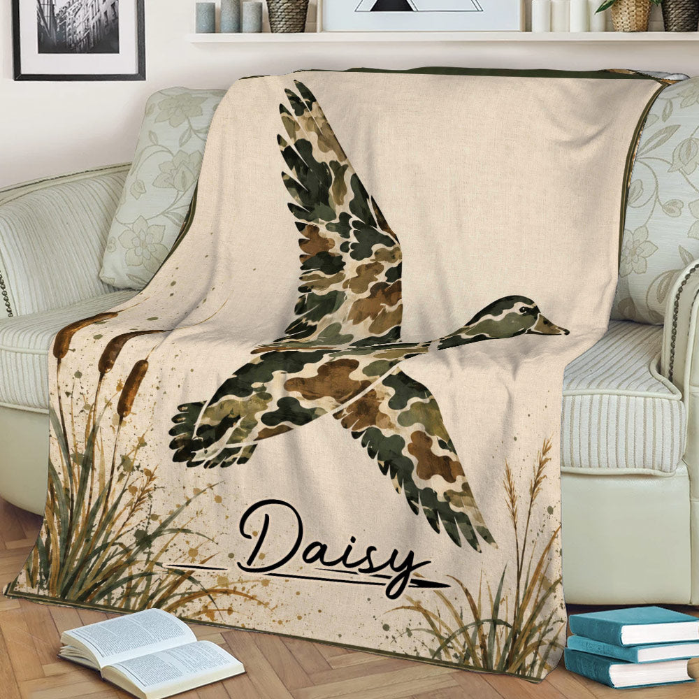 Close view of a duck hunting blanket with a flying waterfowl design, marsh grasses, and rustic camouflage colors