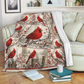 Cardinal throw blanket draped over a sofa with red birds, snowy branches, and berry accents