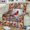 Red cardinal throw blanket draped over a sofa, featuring snowy branches, berries, flowers, and birdhouses