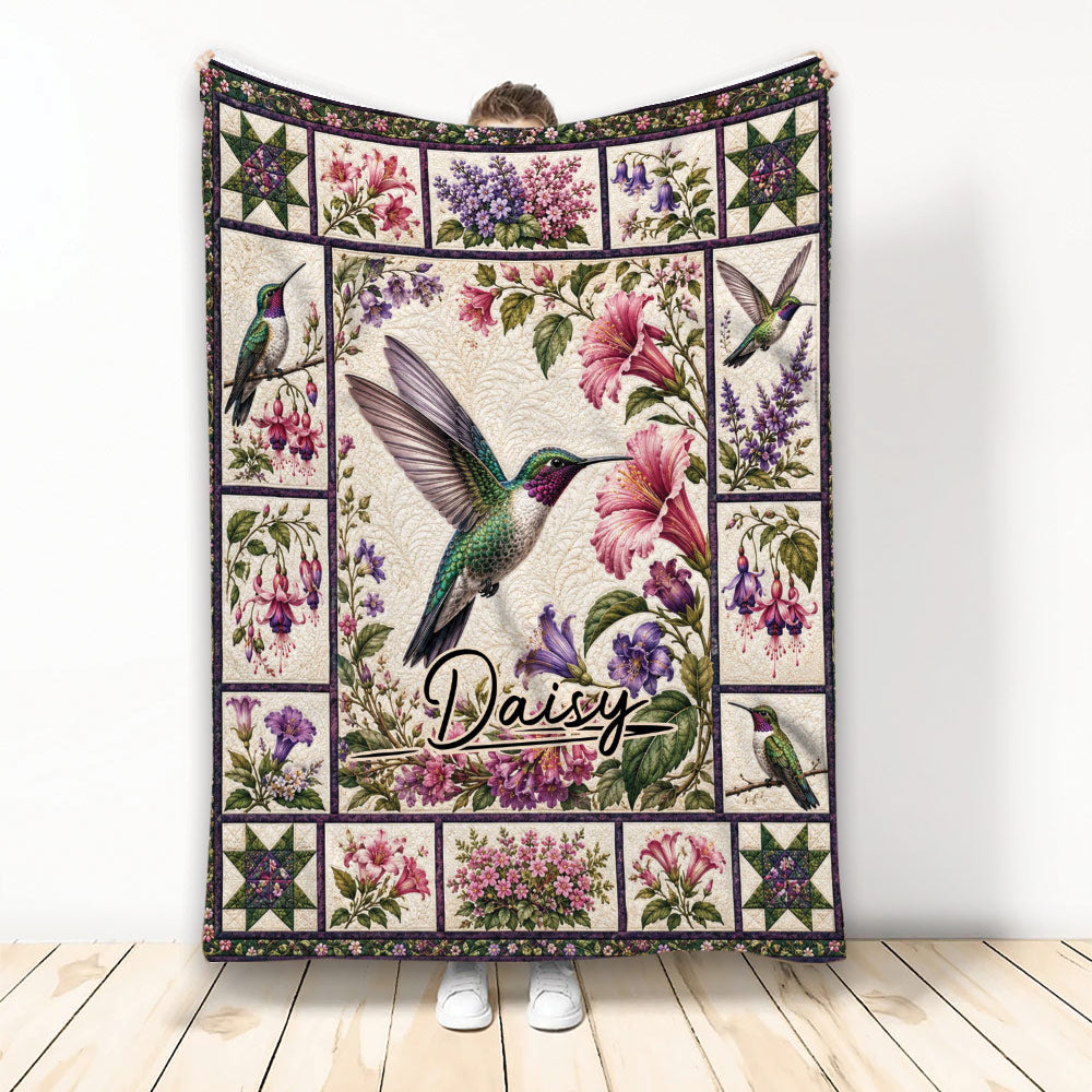 Hummingbird blanket with colorful floral garden artwork displayed against a wall
