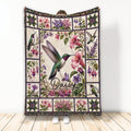 Hummingbird blanket with colorful floral garden artwork displayed against a wall