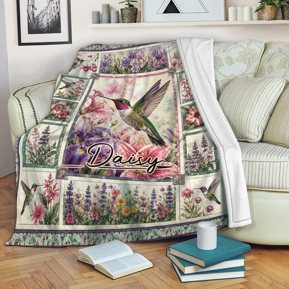 Hummingbird blanket draped over a sofa with floral artwork and a cozy living room setting