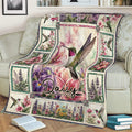 Floral hummingbird throw blanket displayed on a sofa with colorful flowers and botanical artwork